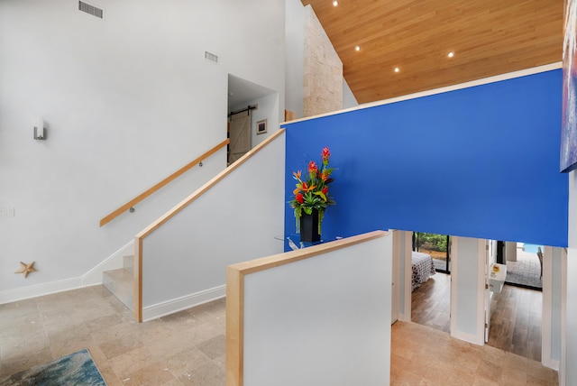 stairs featuring high vaulted ceiling, hardwood / wood-style floors, wood ceiling, and a barn door