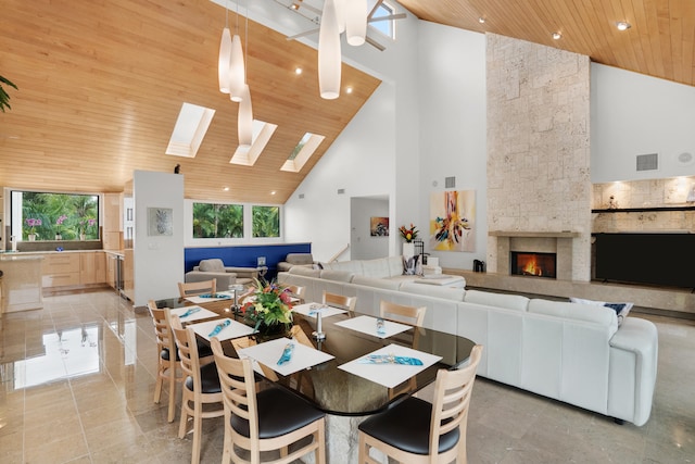 dining area featuring high vaulted ceiling, a large fireplace, a skylight, and wooden ceiling