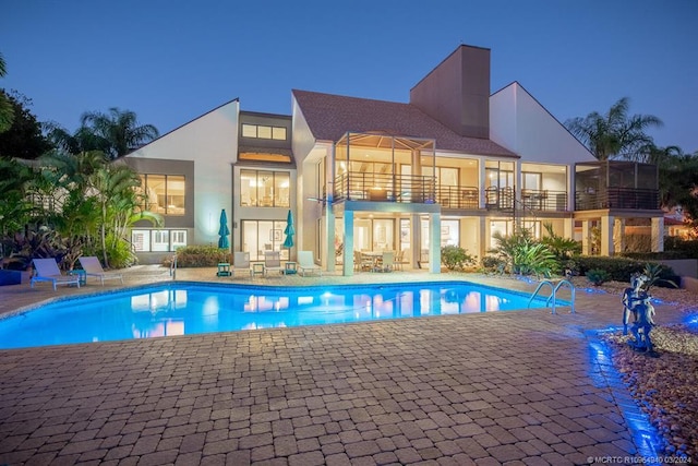 pool at dusk with a patio area