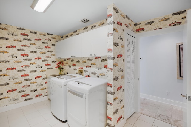 clothes washing area featuring cabinets, washer and dryer, and light tile patterned floors