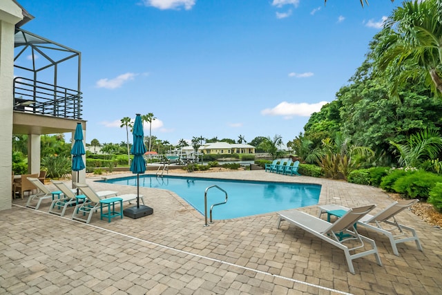 view of swimming pool featuring glass enclosure and a patio area