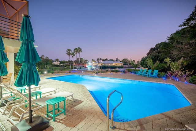 pool at dusk with a patio area