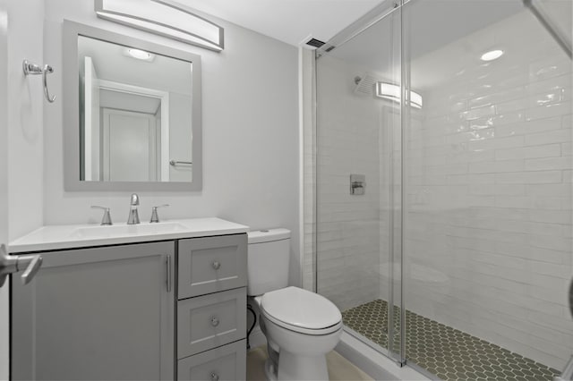 bathroom with vanity, a shower with shower door, and toilet