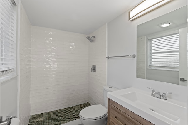 bathroom featuring a tile shower, vanity, and toilet