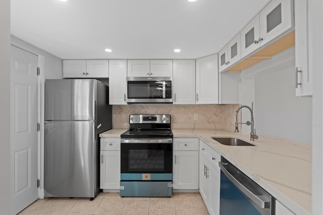 kitchen featuring decorative backsplash, sink, white cabinets, and appliances with stainless steel finishes