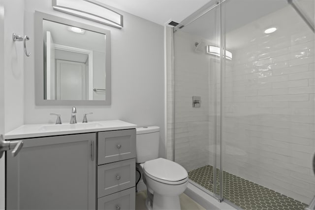 bathroom with a shower with door, vanity, and toilet