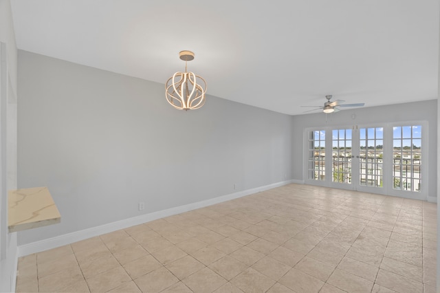 tiled empty room featuring ceiling fan with notable chandelier