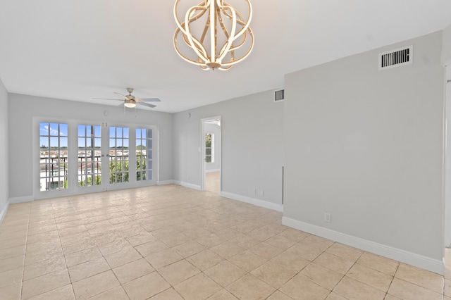 tiled spare room with ceiling fan with notable chandelier