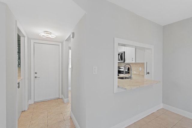 hallway featuring sink and light tile patterned flooring