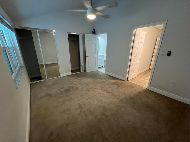 unfurnished bedroom featuring multiple closets, ceiling fan, carpet floors, and vaulted ceiling