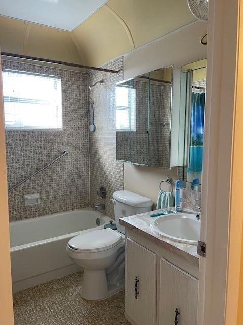 full bathroom featuring tile patterned flooring, vanity, tiled shower / bath combo, and toilet