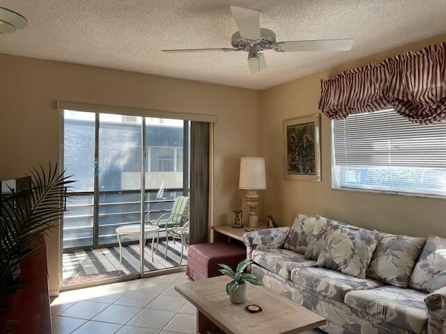 living room with plenty of natural light, ceiling fan, light tile patterned floors, and a textured ceiling