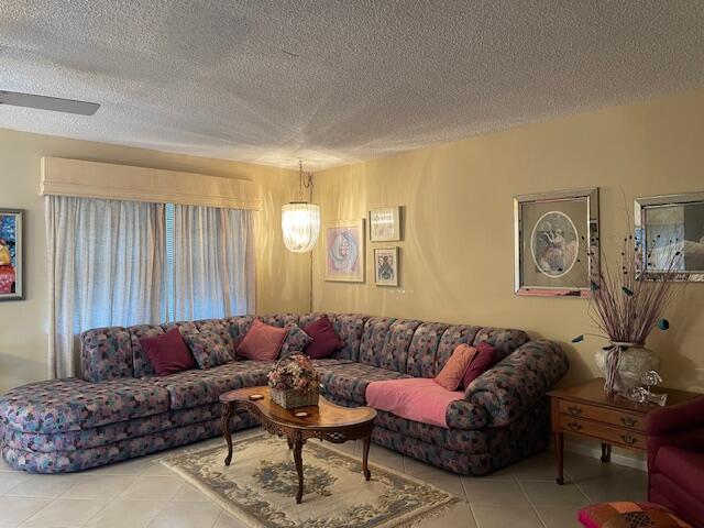 tiled living room featuring a textured ceiling and ceiling fan