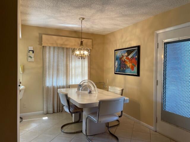 tiled dining area featuring a textured ceiling and a chandelier