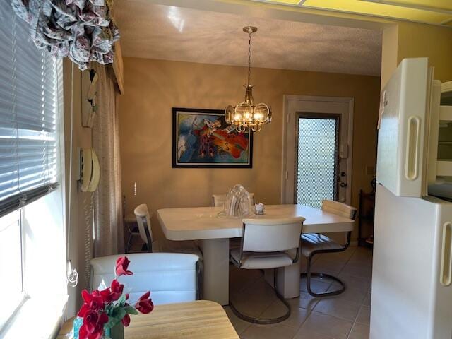 dining area with light tile patterned floors, a textured ceiling, and an inviting chandelier