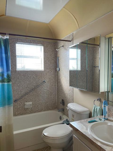 full bathroom with shower / bath combination with curtain, a healthy amount of sunlight, toilet, and vanity