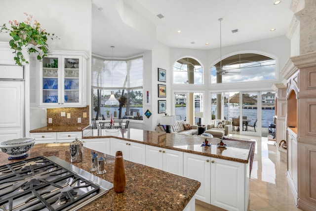 kitchen with dark stone countertops, white cabinetry, and stainless steel gas stovetop