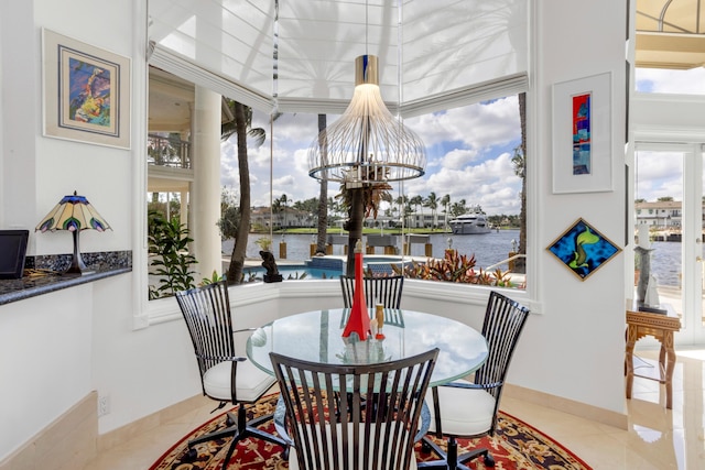 dining room featuring a water view, an inviting chandelier, and light tile patterned flooring