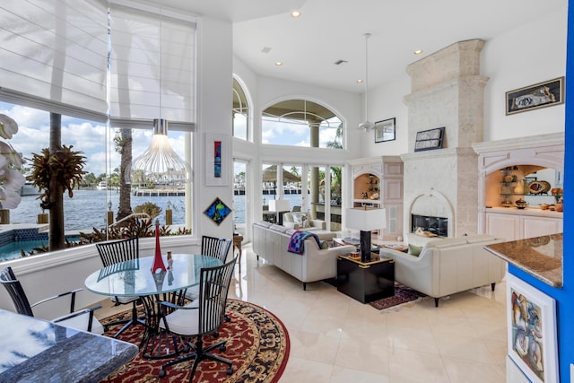 tiled living room featuring a water view, a high ceiling, and a high end fireplace