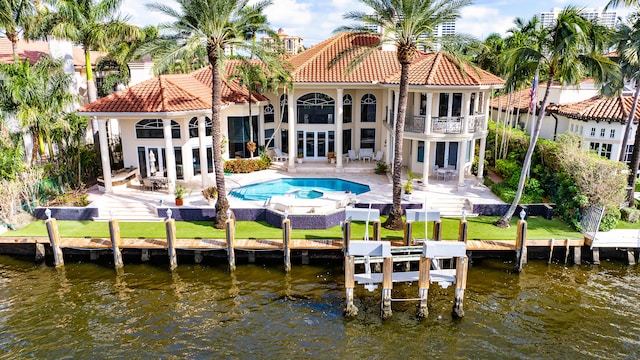 back of property with a patio area, a water view, a balcony, and french doors