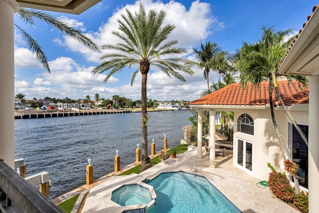 view of pool featuring a water view, an in ground hot tub, and a patio