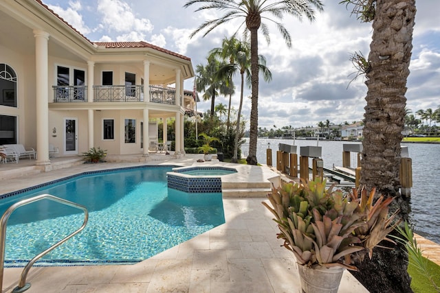 view of swimming pool with a patio area, a water view, and an in ground hot tub