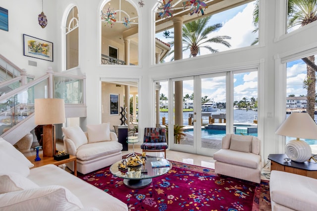 sunroom / solarium featuring french doors and a water view