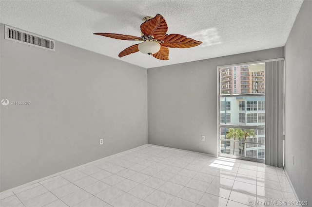 unfurnished room with a textured ceiling, ceiling fan, and light tile patterned floors