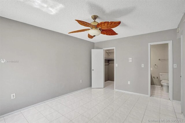 unfurnished bedroom featuring ceiling fan, a textured ceiling, a closet, and a walk in closet