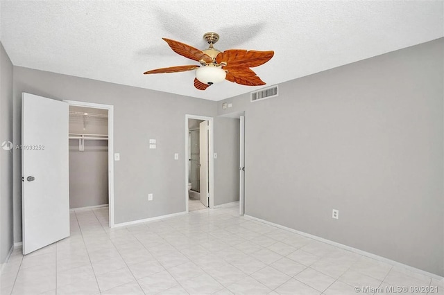 unfurnished bedroom with ceiling fan, a textured ceiling, a closet, and a spacious closet