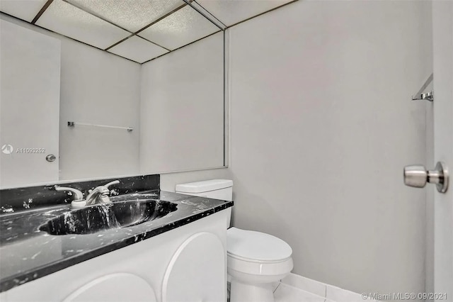 bathroom with a drop ceiling, toilet, vanity, and tile patterned floors