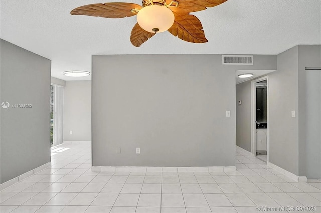 empty room with a textured ceiling, ceiling fan, and light tile patterned flooring