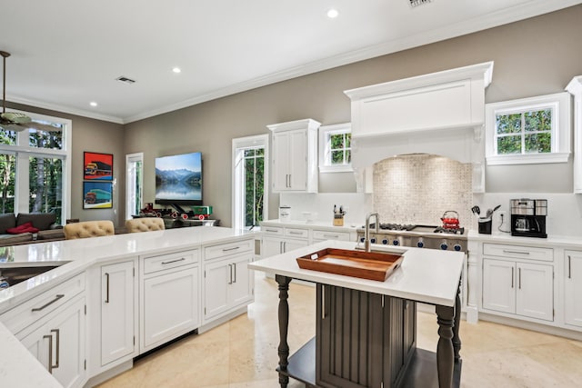 kitchen featuring decorative backsplash, crown molding, light tile patterned floors, white cabinetry, and a breakfast bar area