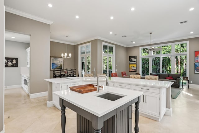 kitchen with white cabinets, decorative light fixtures, a spacious island, and sink