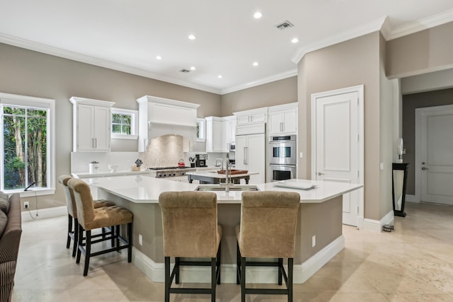 kitchen with white cabinets, ornamental molding, a large island, a kitchen bar, and stainless steel double oven