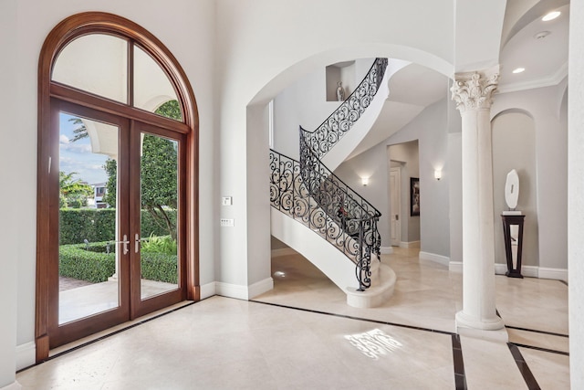 foyer entrance with decorative columns, french doors, and a high ceiling