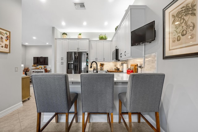 kitchen with a kitchen bar, white cabinetry, kitchen peninsula, and appliances with stainless steel finishes