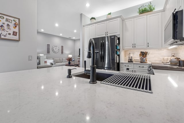 kitchen with light stone counters, white cabinetry, appliances with stainless steel finishes, and tasteful backsplash