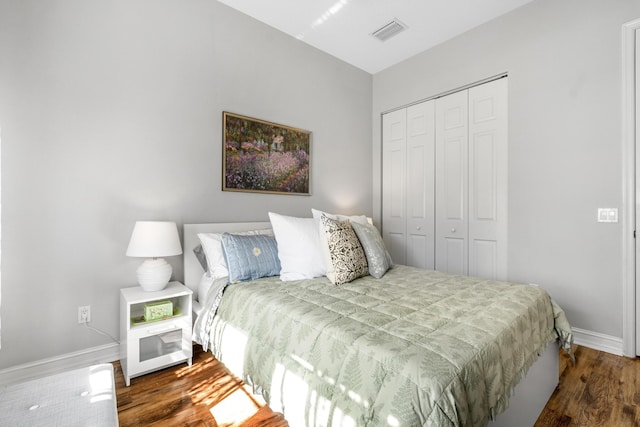 bedroom with dark hardwood / wood-style floors and a closet