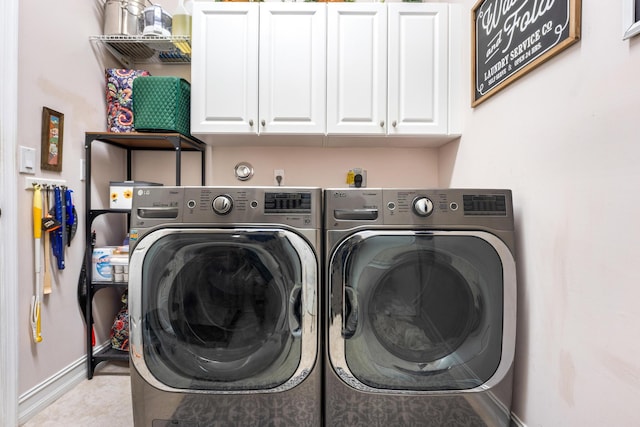 laundry area with separate washer and dryer, light tile patterned floors, and cabinets