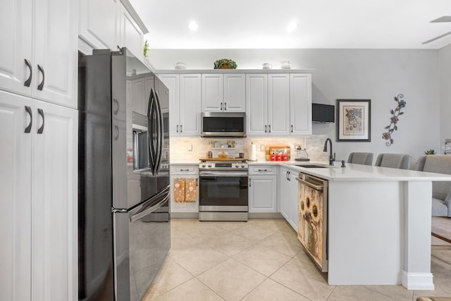 kitchen featuring a breakfast bar, sink, white cabinetry, and stainless steel appliances