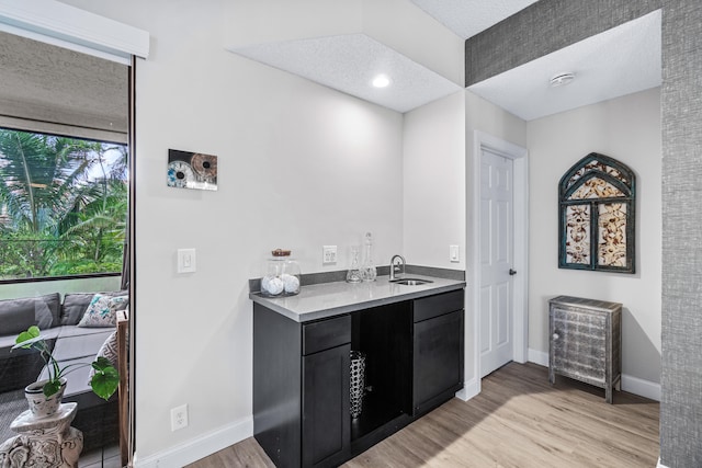 kitchen with sink, a textured ceiling, and light hardwood / wood-style flooring