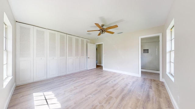 unfurnished bedroom featuring ceiling fan, multiple windows, a closet, and light wood-type flooring