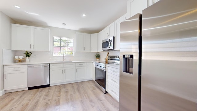 kitchen with stainless steel appliances, white cabinets, and sink