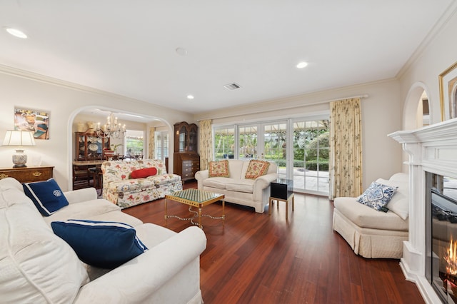 living room featuring crown molding, dark wood-type flooring, and an inviting chandelier