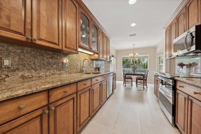 kitchen with sink, stainless steel appliances, pendant lighting, a chandelier, and decorative backsplash