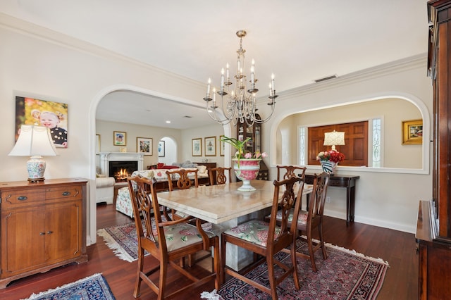 dining room with dark hardwood / wood-style flooring, an inviting chandelier, and ornamental molding