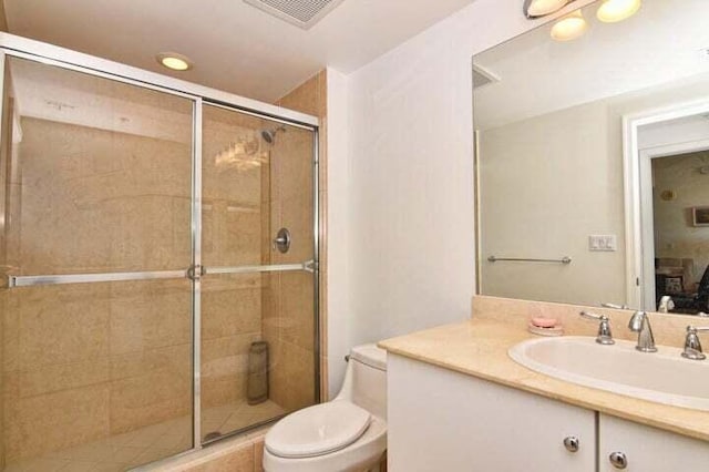 bathroom featuring a shower with shower door, vanity, and toilet