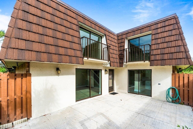 rear view of house featuring a patio and a balcony