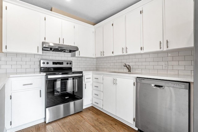 kitchen with appliances with stainless steel finishes, white cabinetry, and range hood